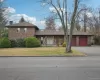 View of front of property with brick siding, asphalt driveway, a chimney, a front lawn, and an attached garage View of front of property with brick siding, asphalt driveway, a chimney, a front lawn, and an attached garage