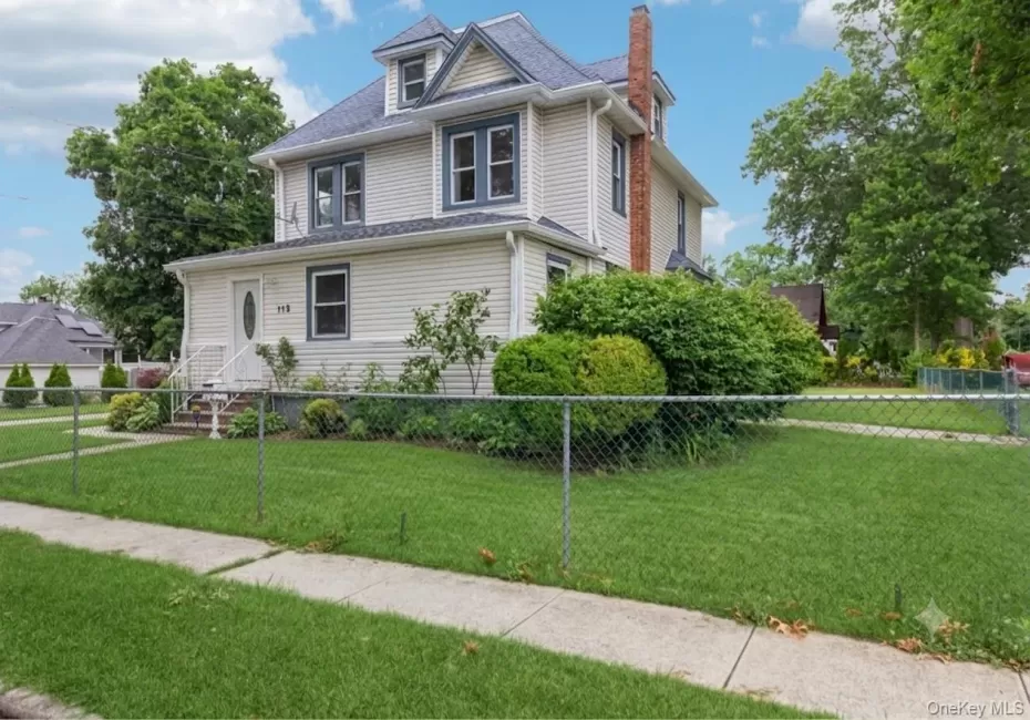 Traditional Colonial revival foursquare-style residence featuring light-colored siding, a dark shingle roof, and a prominent brick chimney Traditional Colonial revival foursquare-style residence featuring light-colored siding, a dark shingle roof, and a prominent brick chimney