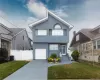 Two-story residence featuring light blue siding, a white garage door, and a light gray concrete driveway Two-story residence featuring light blue siding, a white garage door, and a light gray concrete driveway