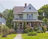 View of front of property featuring covered porch, a shingled roof, a chimney, and a front yard View of front of property featuring covered porch, a shingled roof, a chimney, and a front yard