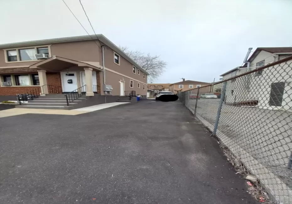 The property features a paved driveway and a two-story exterior with a porch entrance The property features a paved driveway and a two-story exterior with a porch entrance