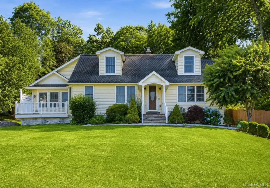 Exterior featuring light yellow siding, a prominent dormer window, and a covered front entry with white railings Exterior featuring light yellow siding, a prominent dormer window, and a covered front entry with white railings