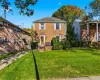 Colonial-style house with brick siding and a front lawn Colonial-style house with brick siding and a front lawn