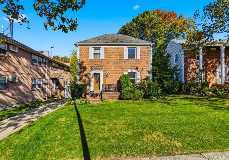 Colonial-style house with brick siding and a front lawn Colonial-style house with brick siding and a front lawn