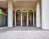 Building entrance featuring large arched windows, a revolving glass door, and substantial cylindrical columns Building entrance featuring large arched windows, a revolving glass door, and substantial cylindrical columns