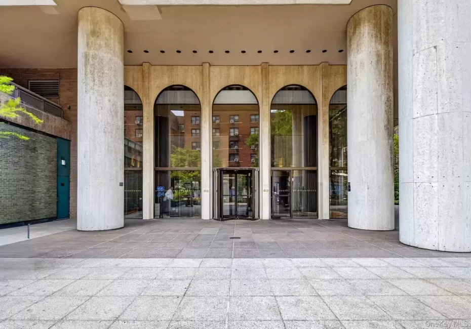 Building entrance featuring large arched windows, a revolving glass door, and substantial cylindrical columns Building entrance featuring large arched windows, a revolving glass door, and substantial cylindrical columns