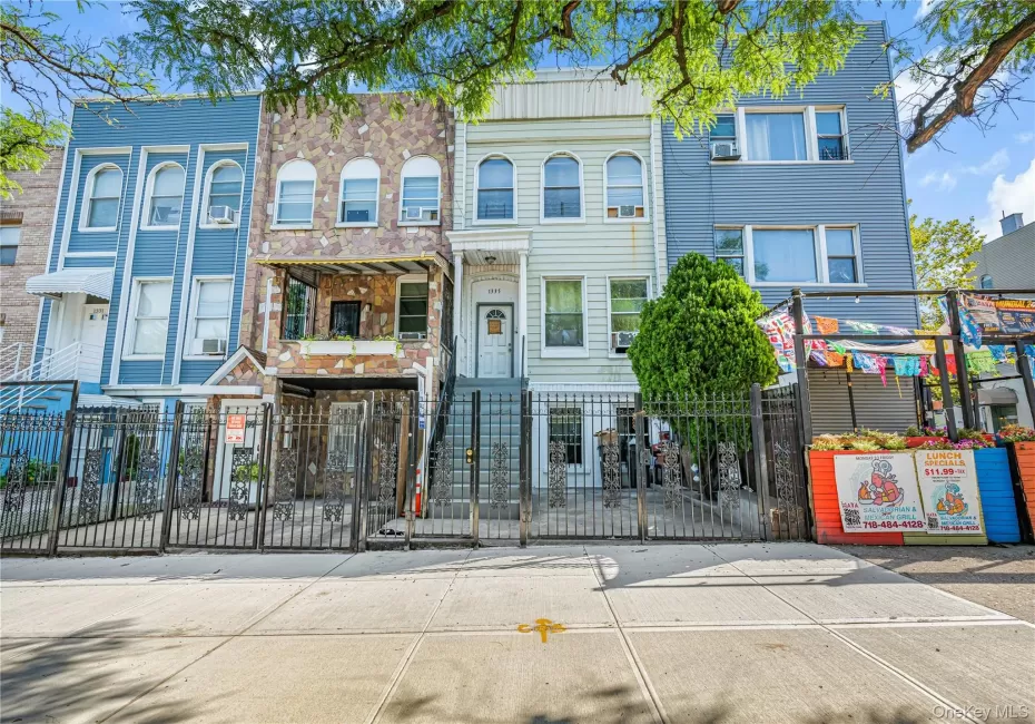 Multi-story residence featuring a stone-clad facade, wrought iron fencing, and an elevated entrance Multi-story residence featuring a stone-clad facade, wrought iron fencing, and an elevated entrance