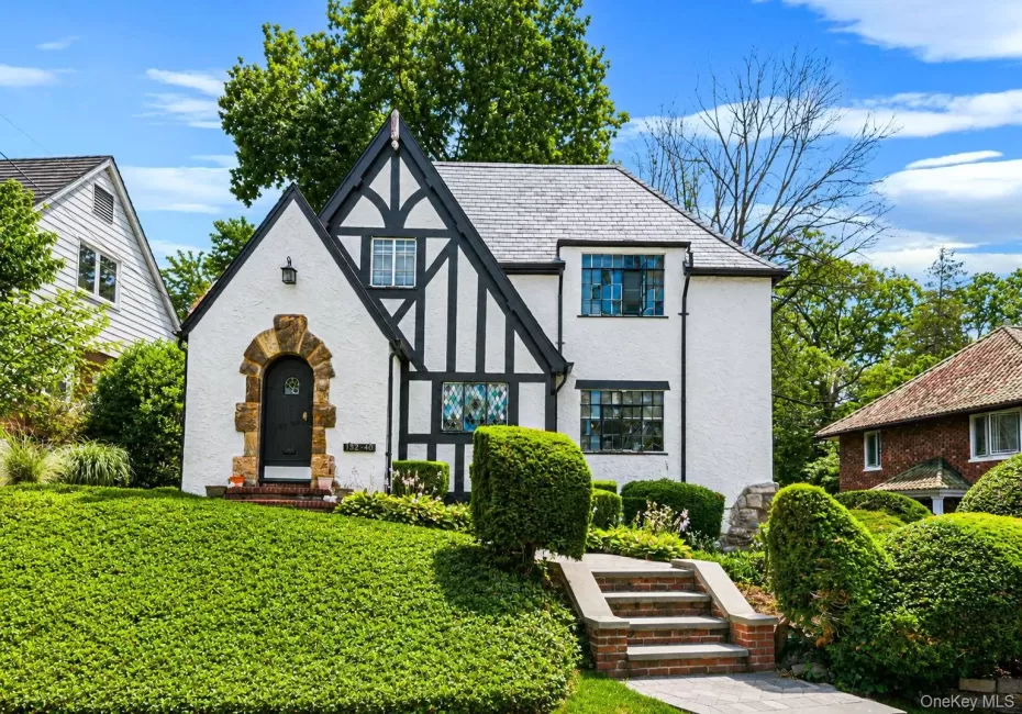 Tudor-style residence featuring a white stucco exterior with dark timber accents and a stone archway entrance Tudor-style residence featuring a white stucco exterior with dark timber accents and a stone archway entrance