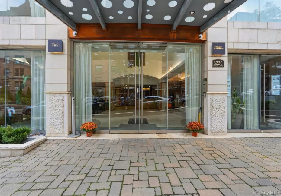 Modern building entrance featuring a stone-clad facade and automatic glass doors Modern building entrance featuring a stone-clad facade and automatic glass doors