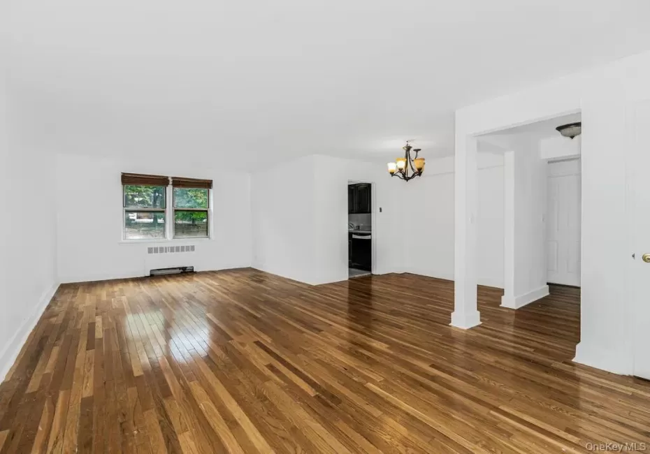 Unfurnished living room featuring radiator heating unit, a chandelier, and dark hardwood / wood-style flooring Unfurnished living room featuring radiator heating unit, a chandelier, and dark hardwood / wood-style flooring