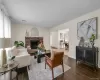 Living space with dark wood-finish flooring, a brick fireplace, and a large window Living space with dark wood-finish flooring, a brick fireplace, and a large window