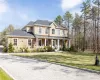 View of front of home featuring a standing seam roof, covered porch, a shingled roof, a metal roof, and a front lawn View of front of home featuring a standing seam roof, covered porch, a shingled roof, a metal roof, and a front lawn