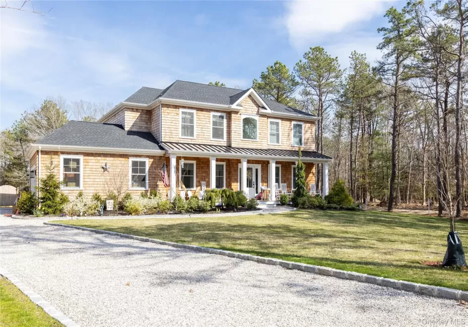 View of front of home featuring a standing seam roof, covered porch, a shingled roof, a metal roof, and a front lawn View of front of home featuring a standing seam roof, covered porch, a shingled roof, a metal roof, and a front lawn