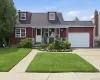 Red-sided residence featuring a covered front porch, white dormer windows, and a single-car garage with a white door Red-sided residence featuring a covered front porch, white dormer windows, and a single-car garage with a white door