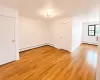 Spacious interior featuring wood-finish flooring, white walls, and a ceiling-mounted light fixture Spacious interior featuring wood-finish flooring, white walls, and a ceiling-mounted light fixture