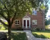 Brick facade residence featuring entryway with red doors, white trim, and transom windows Brick facade residence featuring entryway with red doors, white trim, and transom windows