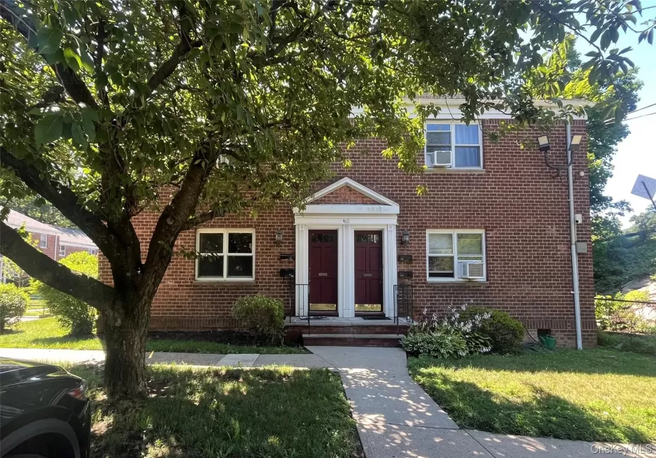 Brick facade residence featuring entryway with red doors, white trim, and transom windows Brick facade residence featuring entryway with red doors, white trim, and transom windows