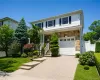 Two-story residence featuring stone and siding facade, a front porch with white railings, and a two-car garage with a panel door Two-story residence featuring stone and siding facade, a front porch with white railings, and a two-car garage with a panel door