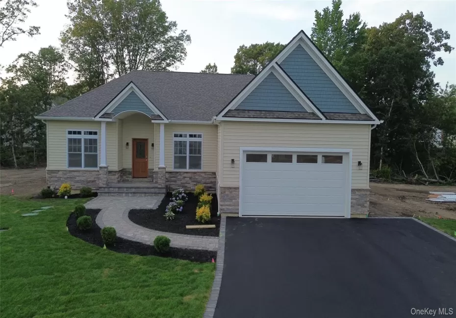 Craftsman house with asphalt driveway, stone siding, a front lawn, a shingled roof, and a garage Craftsman house with asphalt driveway, stone siding, a front lawn, a shingled roof, and a garage