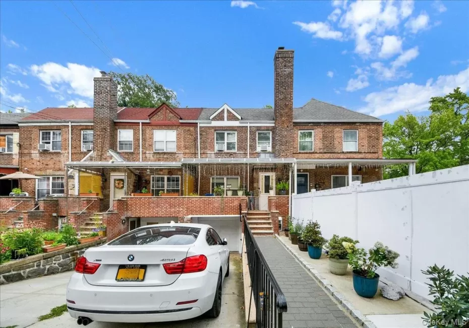 Brick exterior townhouse featuring a covered front entry, an attached garage, a paved driveway, a side walkway, and a privacy fence Brick exterior townhouse featuring a covered front entry, an attached garage, a paved driveway, a side walkway, and a privacy fence