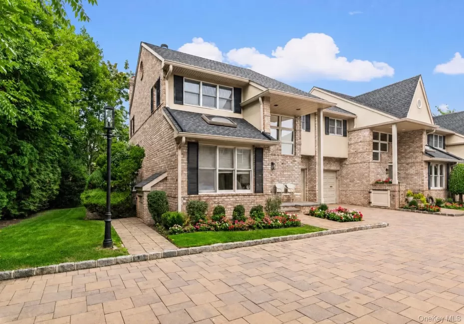 END UNIT Brick facade residence featuring a paver driveway, manicured landscaping, a paved walkway, and a decorative lamppost END UNIT Brick facade residence featuring a paver driveway, manicured landscaping, a paved walkway, and a decorative lamppost