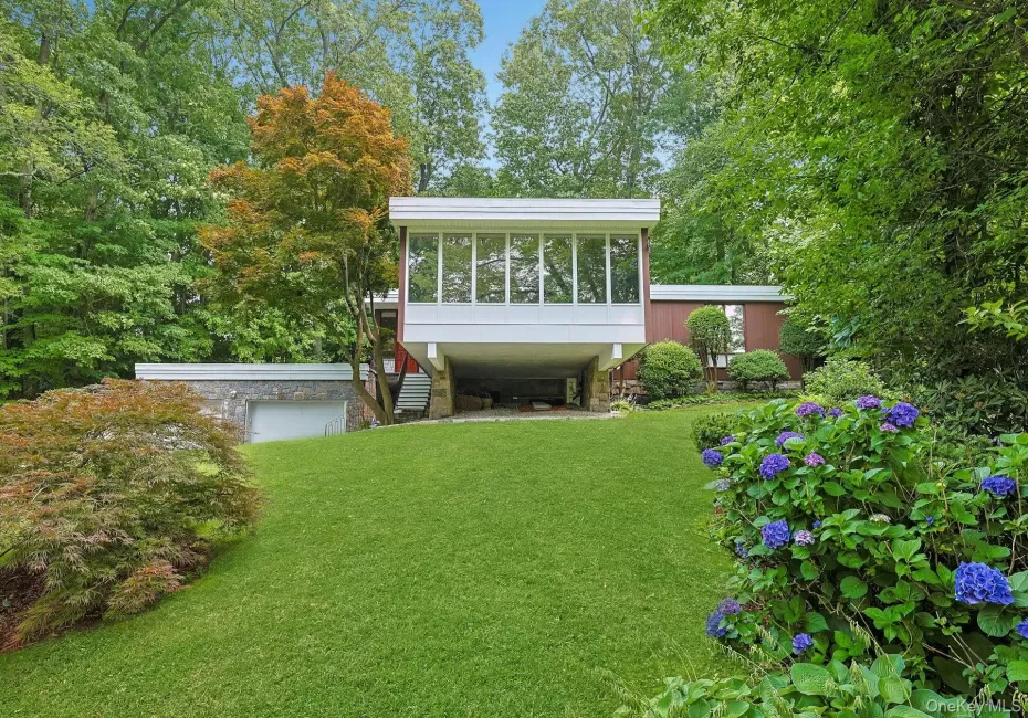 A striking Mid-Century Modern residence nestled among mature trees, showcasing clean architectural lines, dramatic walls of glass, and exceptional curb appeal. A striking Mid-Century Modern residence nestled among mature trees, showcasing clean architectural lines, dramatic walls of glass, and exceptional curb appeal.