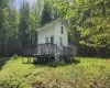 View of home's exterior with a storage unit, a wooden deck, an outdoor structure, and a view of trees View of home's exterior with a storage unit, a wooden deck, an outdoor structure, and a view of trees