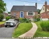 Brick exterior residence featuring a prominent bay window with white shutters, a distinctive blue entry door, and a dedicated driveway Brick exterior residence featuring a prominent bay window with white shutters, a distinctive blue entry door, and a dedicated driveway