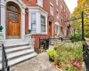 Brick facade row house featuring a paneled wood-finish entry door with leaded glass, an arched transom, and white trim Brick facade row house featuring a paneled wood-finish entry door with leaded glass, an arched transom, and white trim