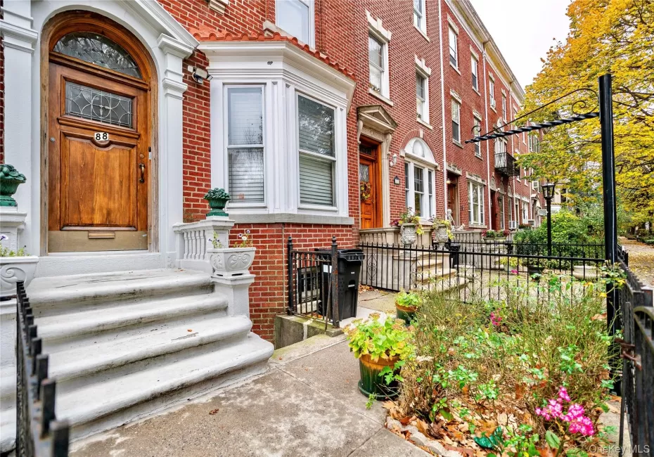 Brick facade row house featuring a paneled wood-finish entry door with leaded glass, an arched transom, and white trim Brick facade row house featuring a paneled wood-finish entry door with leaded glass, an arched transom, and white trim