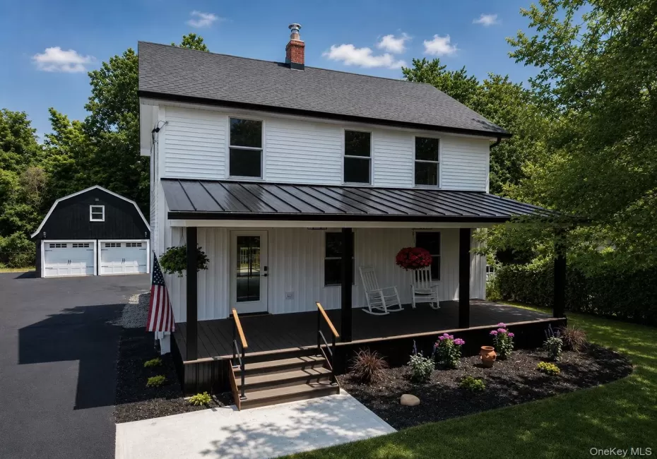 White siding exterior with a dark-paneled roof and covered front porch White siding exterior with a dark-paneled roof and covered front porch