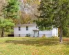 View of front of property featuring a front yard, a chimney, and view of scattered trees View of front of property featuring a front yard, a chimney, and view of scattered trees
