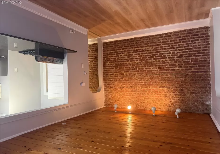 Entrance to living room and kitchen with brick wall and hardwood floors Entrance to living room and kitchen with brick wall and hardwood floors
