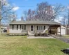Ranch-style house featuring an outdoor structure, aphalt driveway, a front yard, a carport, and a shingled roof Ranch-style house featuring an outdoor structure, aphalt driveway, a front yard, a carport, and a shingled roof