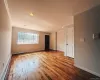 Spacious living area featuring wood-finish flooring, ample natural light from a large window, recessed lighting, and crown molding. Spacious living area featuring wood-finish flooring, ample natural light from a large window, recessed lighting, and crown molding.