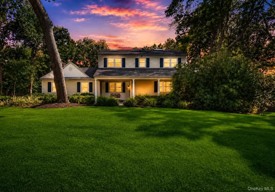 Two-story residence featuring a covered front porch, dark shutters, and white window trim Two-story residence featuring a covered front porch, dark shutters, and white window trim
