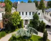 White Colonial-style residence featuring a gray shingle roof and multiple dormer windows White Colonial-style residence featuring a gray shingle roof and multiple dormer windows