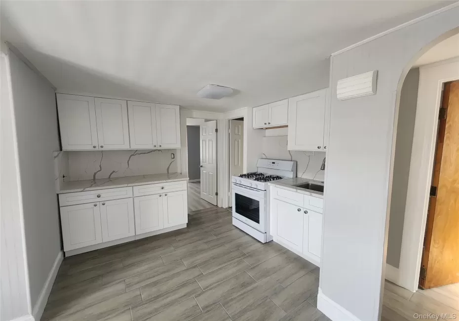 Kitchen featuring white cabinetry, a gas range, a single basin sink, and tile flooring granit countertops. Kitchen featuring white cabinetry, a gas range, a single basin sink, and tile flooring granit countertops.