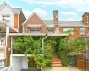 Brick facade featuring a recessed garage with a wood-finish door, a covered porch with an awning, and exterior steps leading to the entrance Brick facade featuring a recessed garage with a wood-finish door, a covered porch with an awning, and exterior steps leading to the entrance