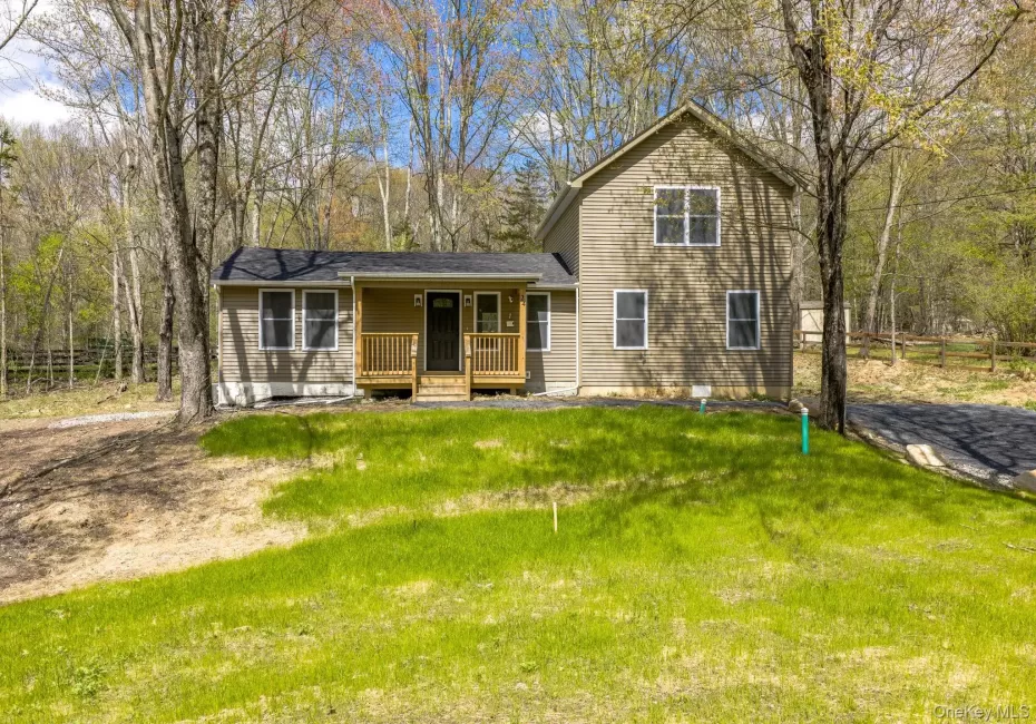 Two-story residence featuring light brown horizontal siding, a dark asphalt shingle roof, and multiple windows with white trim Two-story residence featuring light brown horizontal siding, a dark asphalt shingle roof, and multiple windows with white trim