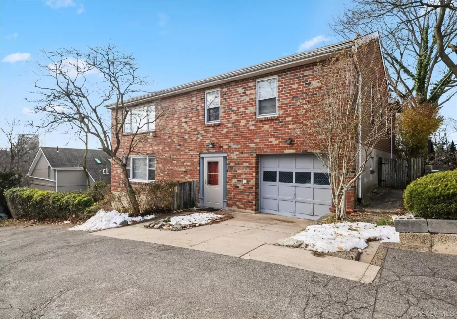 Colonial home featuring brick siding, a garage, and concrete driveway Colonial home featuring brick siding, a garage, and concrete driveway