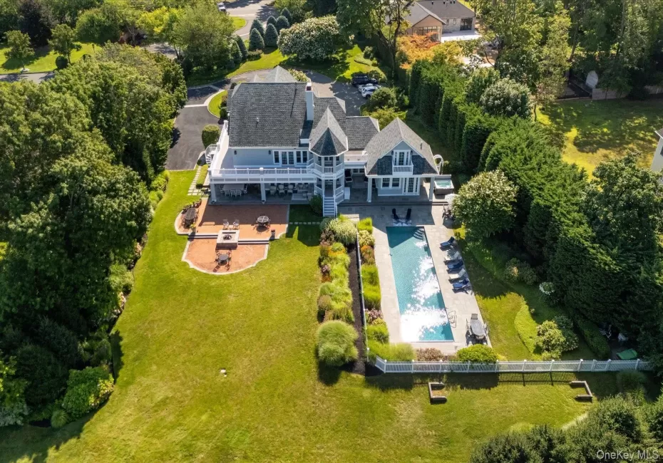 Expansive backyard featuring a rectangular swimming pool, a substantial paver patio with a built-in fire pit, and a spacious upper-level balcony Expansive backyard featuring a rectangular swimming pool, a substantial paver patio with a built-in fire pit, and a spacious upper-level balcony