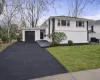 Modern split-level residence featuring a white facade with dark trim accents Modern split-level residence featuring a white facade with dark trim accents