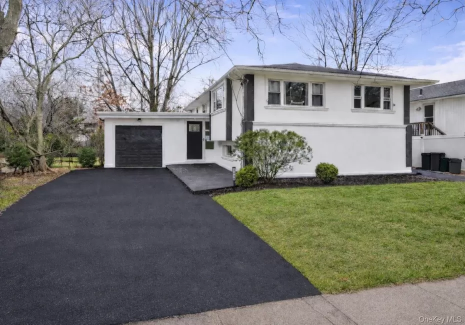 Modern split-level residence featuring a white facade with dark trim accents Modern split-level residence featuring a white facade with dark trim accents