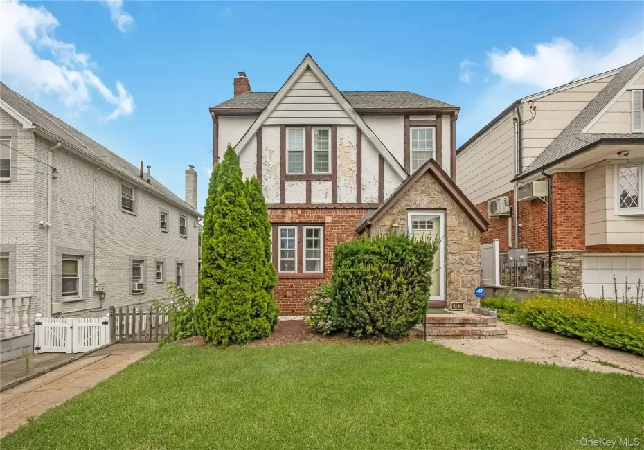 Tudor-style facade featuring brick, stone, and stucco finishes with decorative timber framing Tudor-style facade featuring brick, stone, and stucco finishes with decorative timber framing