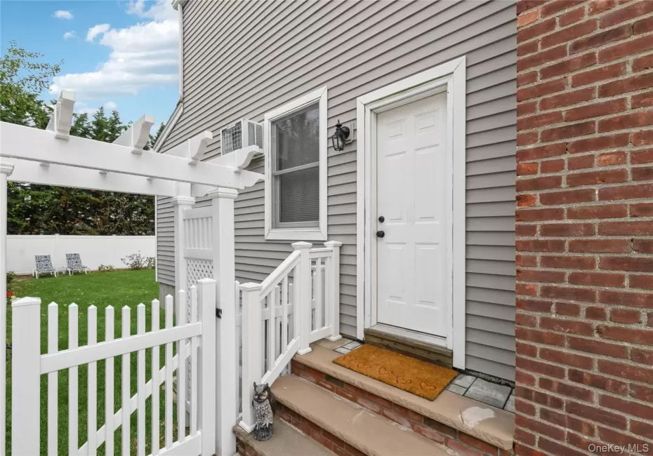 Exterior features include gray horizontal siding, a paneled entry door with a black fixture, and a red brick facade Exterior features include gray horizontal siding, a paneled entry door with a black fixture, and a red brick facade
