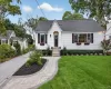 Charming white siding residence featuring a dark shingle roof and black window shutters Charming white siding residence featuring a dark shingle roof and black window shutters