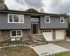 Raised ranch with driveway, a garage, stone siding, entry steps, and a chimney Raised ranch with driveway, a garage, stone siding, entry steps, and a chimney
