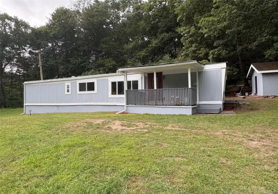 Manufactured / mobile home featuring a front yard and a covered porch Manufactured / mobile home featuring a front yard and a covered porch