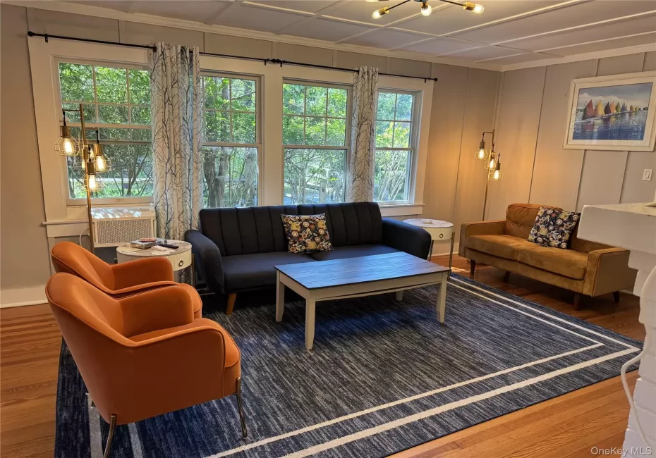 Living room with wood finished floors, healthy amount of natural light, a chandelier, and ornamental molding Living room with wood finished floors, healthy amount of natural light, a chandelier, and ornamental molding